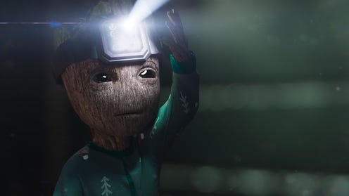 Baby groot holding a digital watch on his head which is shining like a flashlight