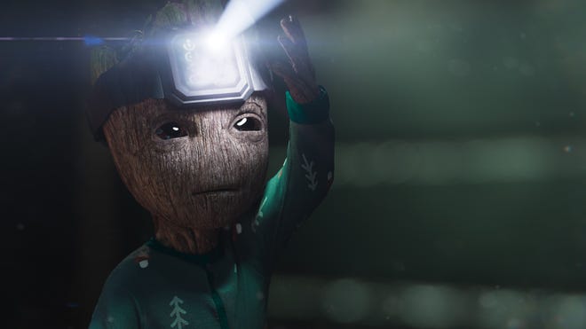 Baby groot holding a digital watch on his head which is shining like a flashlight