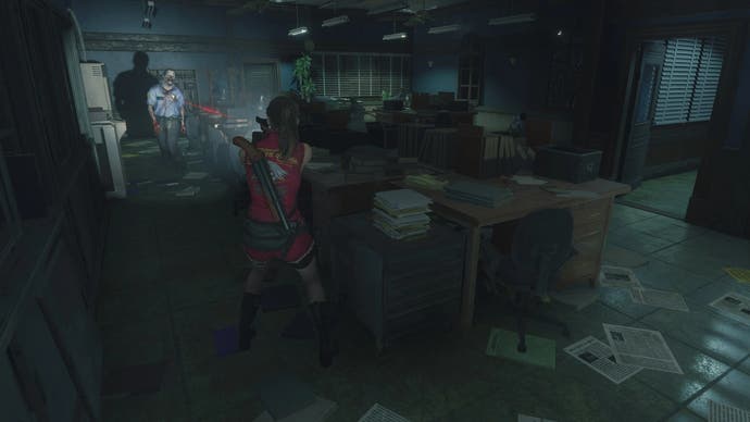 Claire در حالت دوربین ثابت Resident Evil 2 Remake یک زامبی را در یک دفتر شلوغ هدف قرار می دهد.