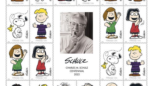 sheet of stamps featuring various Peanuts characters around a portrait of Charles M Schulz