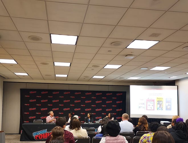 Panelists of the Whats next for webtoons sitting behind a table in front of a new York comic Con screen