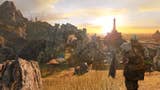 A sunset scene within Dark Souls 2, as the player character in a suit of armour looks out to the horizon behind a scene of towering rocks.