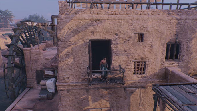 Basim stands on a small balcony outside of a watermill in Assassin's Creed Mirage