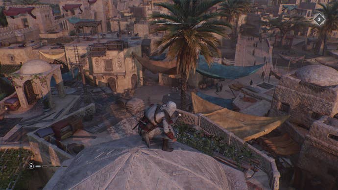 Basim stands atop a dome building looking at some colourful canopies in Assassin's Creed Mirage