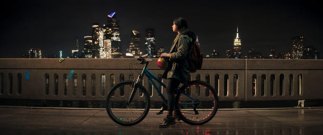 Ms. Marvel still Iman Vellani as Kamala Khan on a bike looking at the night sky