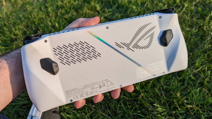 The rear panel on an Asus ROG Ally, which is being held in a hand above some grass,