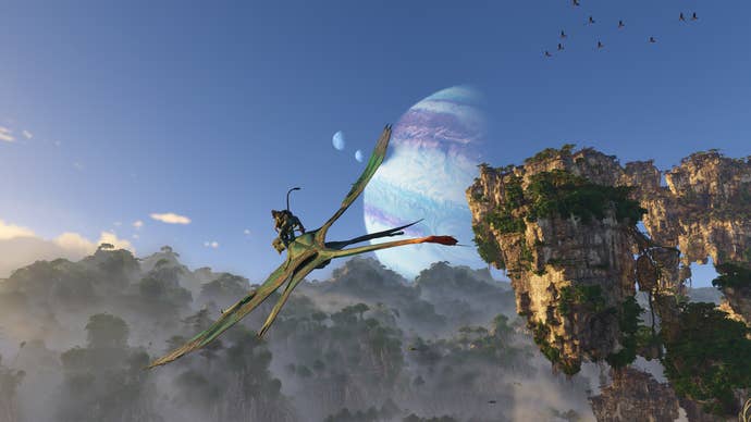 Un Na'vi monta un ikran, una criatura aviar parecida a un reptil, contra los cielos azules de Avatar: Fronteras de Pandora, con un par de planetas visibles en el cielo.