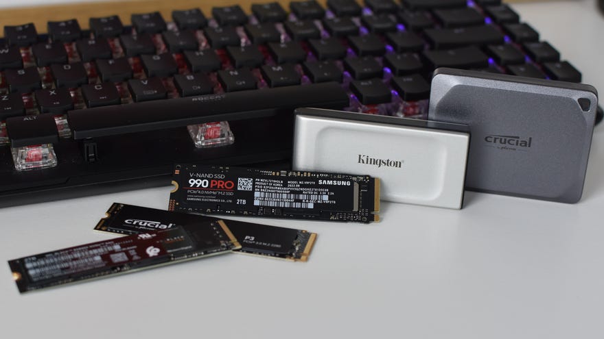 Several SSDs laid out in front of a gaming keyboard.