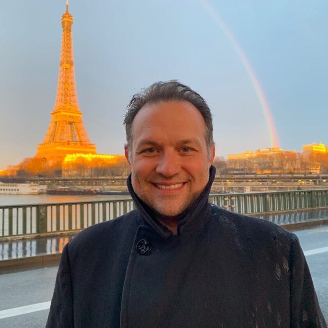 Image of Chip Mosher in front of Eiffel Tower with a rainbow in the background