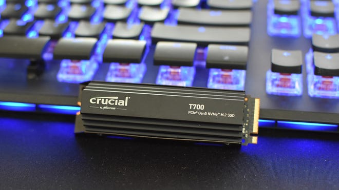 The Crucial T700, with its heatsink, learning against a gaming keyboard.