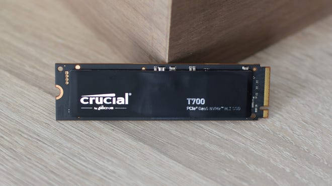 The no-heatsink model of the Crucial T700 SSD resting on a table.