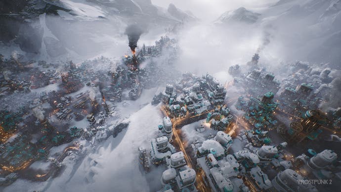 Una toma cercana de una ciudad en Frostpunk 2, que nos permite ver algunos de los detalles adicionales que ofrece Unreal Engine 5 en la secuela.  La nieve se acumula pesadamente sobre los edificios oscuros, mientras que hay una colorida mancha naranja de actividad en las carreteras, similar a una exposición prolongada.