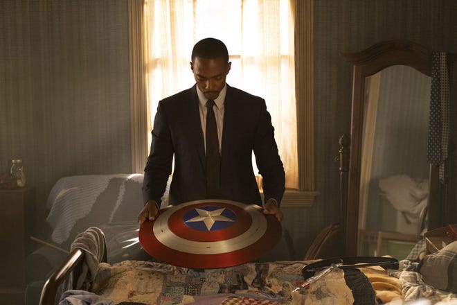 Sam Wilson in a suit holding the Captain America shield