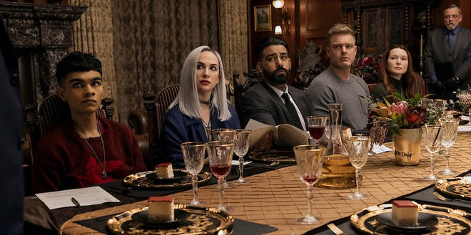 Several characters from Fall of the House of Usher sitting at a table.