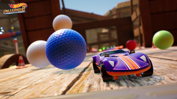 Ein Hot Wheels Auto umfährt große Golfbälle auf einer Rennstrecke.