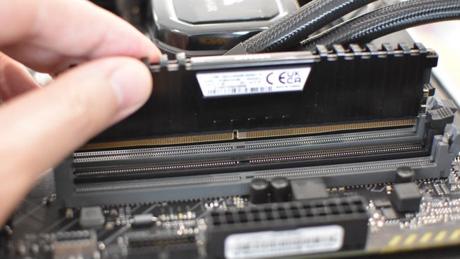 Step 2 of how to install RAM: line up a RAM stick with the slot, making sure the central notch aligns.