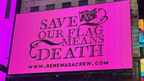 Photograph of pink billboard that reads Save Our Flag Mans Death and www.renewasacrew.com