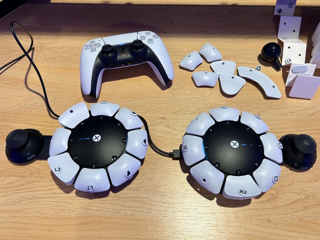 Photo of two Access controllers plus extra button parts next to a DualSense
