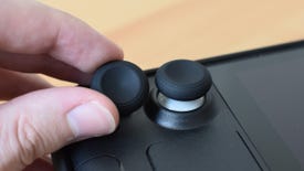 The JSAUX Steam Deck Thumb Grip Caps. One is applied to the Steam Deck's left thumbstick, the other is being held next to it.