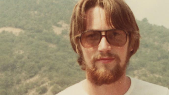 A photo of Jeff Minter when he was young, with sunglasses and a beard.  The yellowing of the photo suggests the 70s or early 80s. From Llamasoft: The Jeff Minter Story