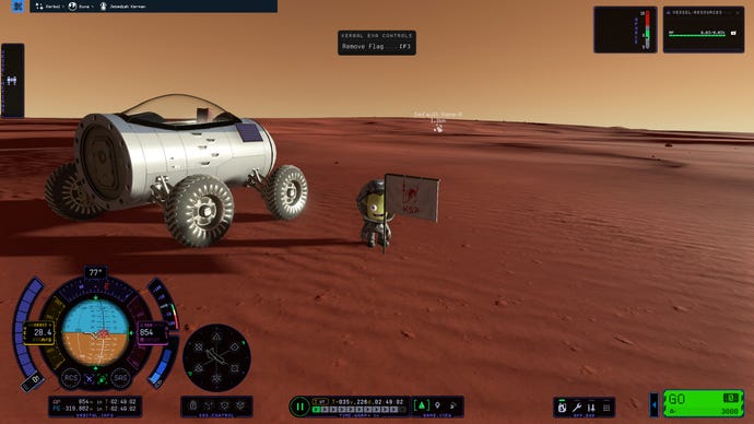 A kerbal from Kerbal Space Program 2 stands on a red-sanded planet next to a planted KSP flag