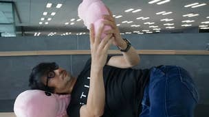 Kojima holds a Cryptobiosis plushie, while lying on another