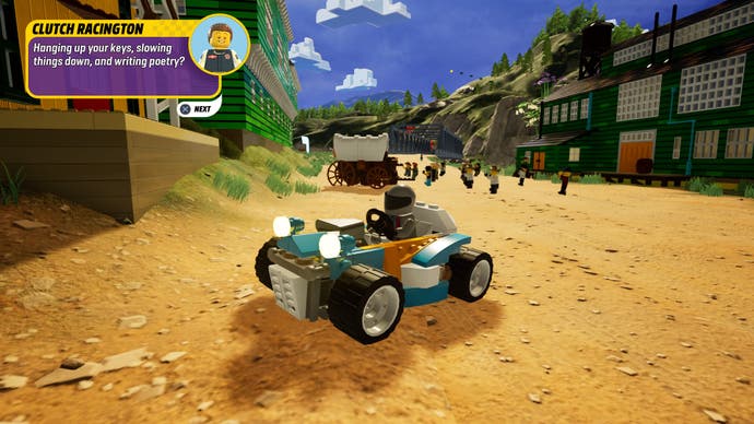 Lego 2K Drive review screenshot, showing one of the main streets in Prospecto Valley, a dusty track flanked by boardwalks, with a go-kart parked in centre frame.