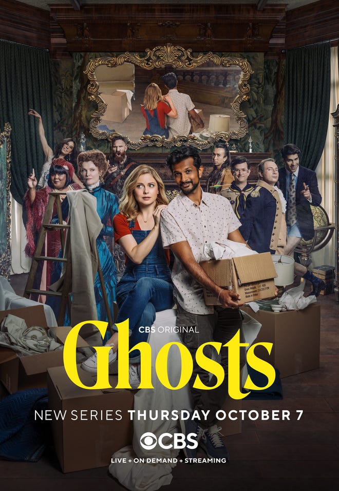 Poster for Ghosts that features a man and a woman with a box, with a group of people in different eras of period dress behind them