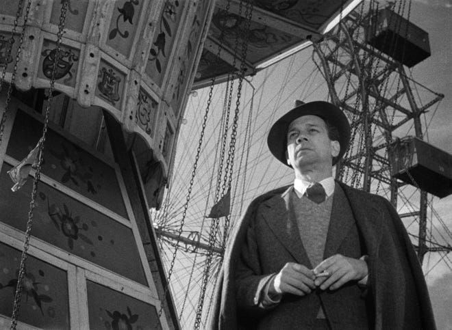 Black and white still featuring Joseph Cotten standing in front of a ferris wheel