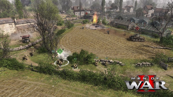 Soldiers take cover behind a stone wall in a countryside village in Men Of War 2