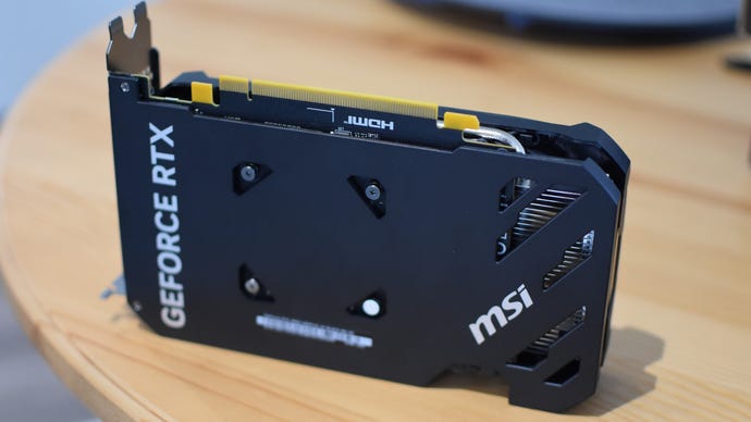 Kad grafik MSI Geforce RTX 4060 Ventus 2X duduk di atas meja, dengan backplate yang menghadap kamera