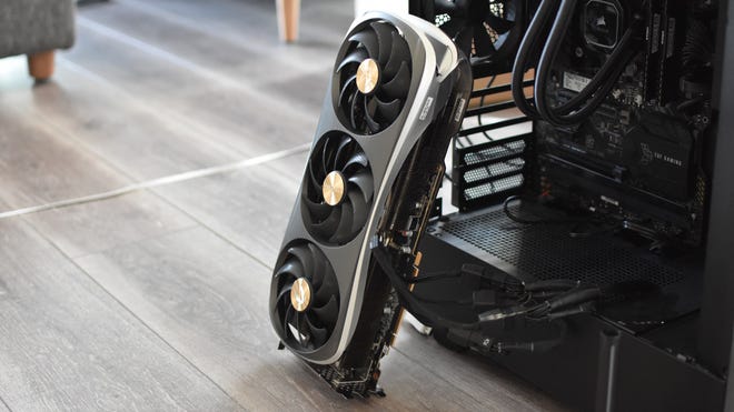 A Zotac Gaming GeForce RTX 4090 Amp Extreme Airo graphics card propped up against a PC case.