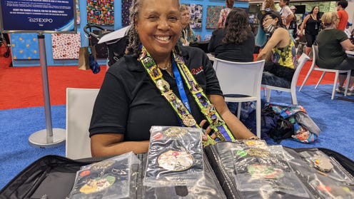 Jeanette Burton smiling, showcasing her book of pins and Maleficent lanyard