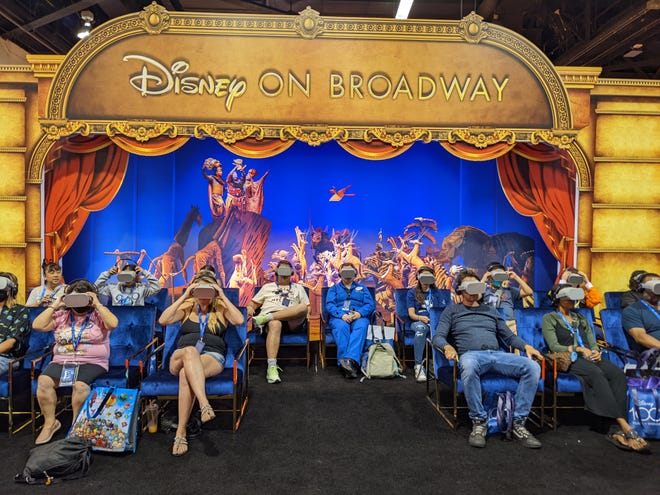 A photograph of people wearing VR goggles under a sign that says Disney on Broadway
