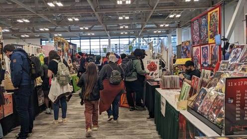 Photograph of artists alley featuring a busy group looking at different booths