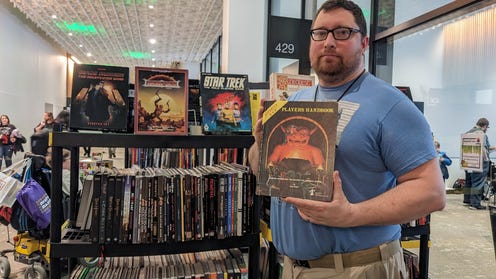 David Carnahan holding a copy of Dungeons and Dragons in front of the library