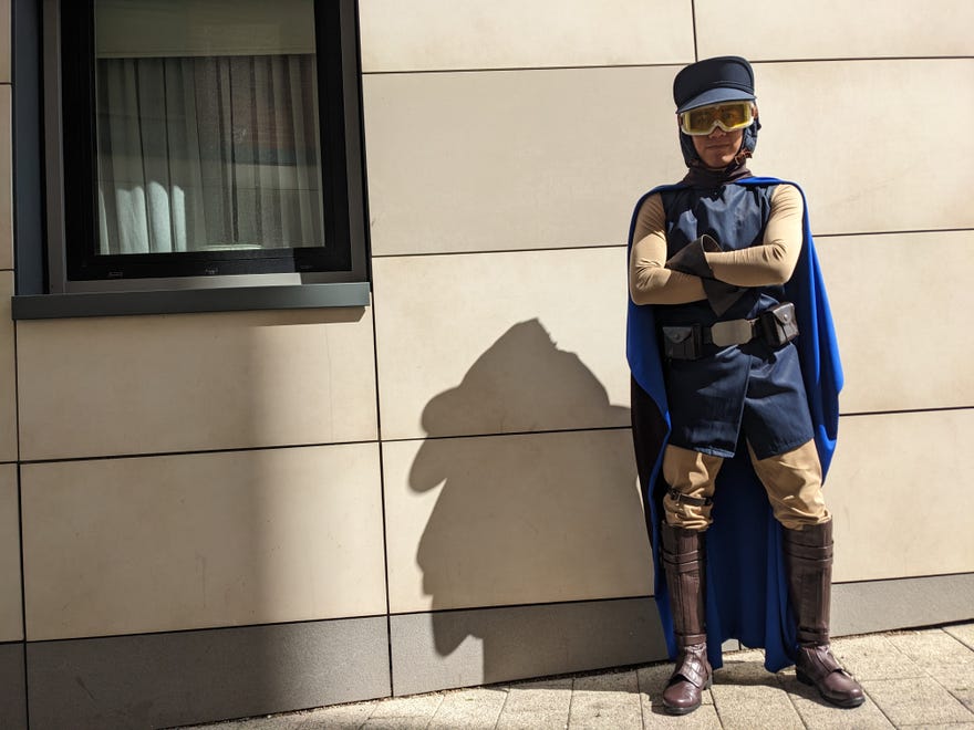 A photograph of a cosplayer leaning against a wall