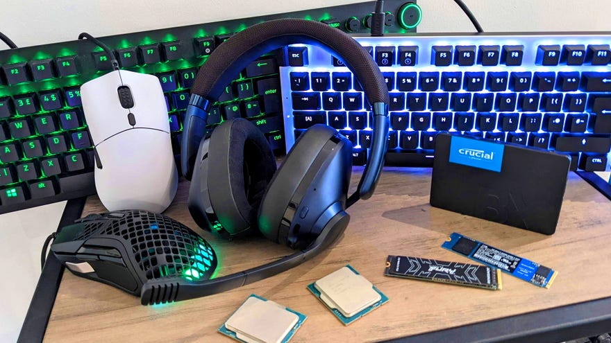 An assortment of PC gaming peripherals and components arranged on a small table, including keyboards, a mouse, a gaming headset and some SSDs.