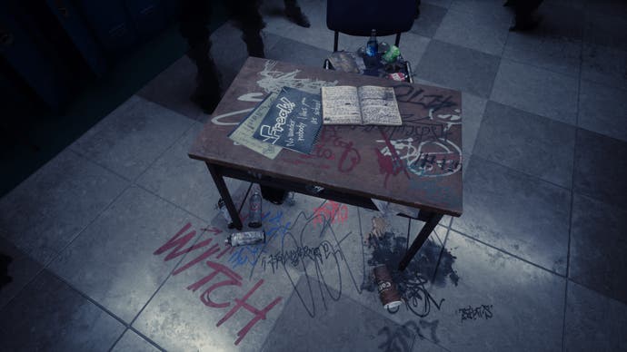 Silent Hill La captura de pantalla del mensaje corto.  Un pupitre se encuentra en medio de un pasillo.  En él aparecen grafitis con insultos, incluida la palabra "bruja".  Es un recordatorio de una escena similar de la primera película/juego de Silent Hill.
