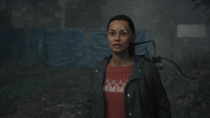 Screenshot of Alan Wake 2's Saga Anderson, wearing a red knitted sweater and black waterproof jacket, as she arrives at the trailer park in Watery.