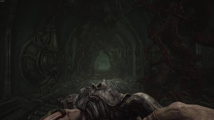 The player faces a long corridor with an alien dangling inside in Act 3 of Scorn