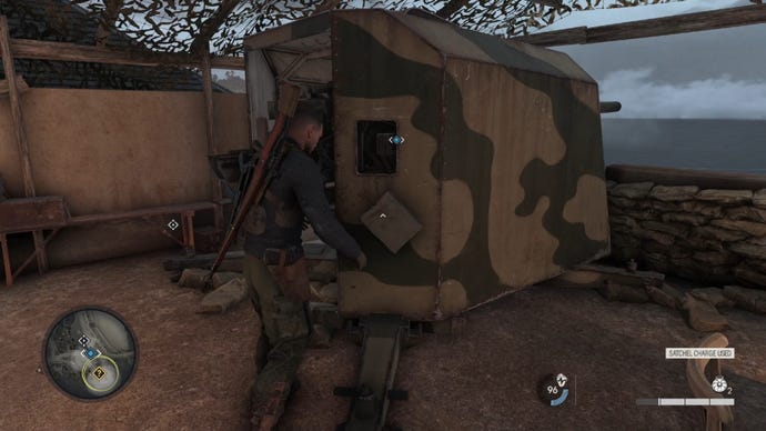 Sniper Elite 5 screenshot of the main character planting a satchel charge explosive on a large turret in a bunker
