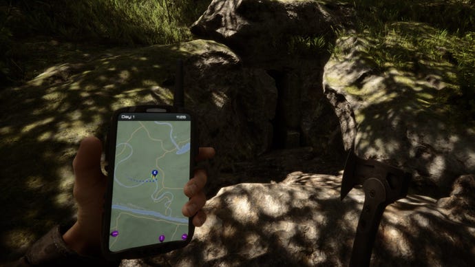 선수는 숲의 아들에게 GPS를 들고 동굴 옆에 서 있습니다