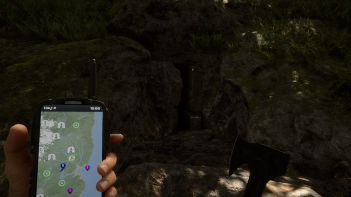 Un jugador mira la entrada de una cueva oscura mientras sostiene un GPS y un hacha en Sons of the Forest.