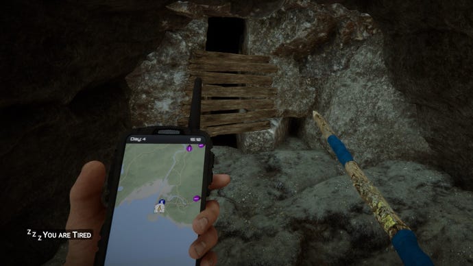 Hráč stojí pri vchode do jaskyne so svojimi GPS v synoch lesa