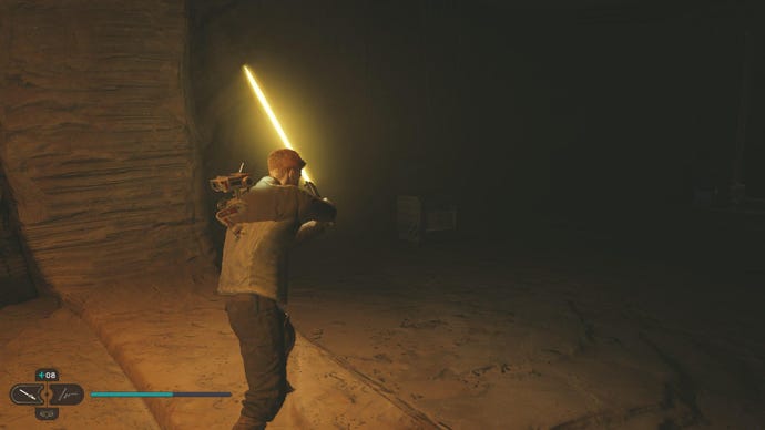 Jedi Survivor screenshot showing Cal holding a yellow lightsaber up to illuminate a chest in the darkness.