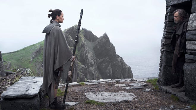 Star Wars The Last Jedi Daisy Ridley as Rey, looking at Mark Hamill as Luke Skywalker as he stands in the entrance of a stone doorway