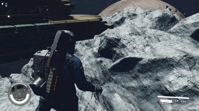 Der Spieler spaziert über einem Asteroiden im Weltraum herum, wobei sein Raumschiff in der oberen linken Ecke sichtbar ist.