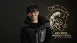Hideo Kojima smiles at the camera in front of a Kojima Productions logo.