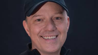 Mass Effect's former lead writer Mac Walters smiles at the camera wearing a baseball cap, now at his new studio Worlds Untold.